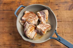 This is a picture of pork chunks being seared in a skillet.