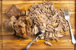 This is a picture of the pork being shredded once it's cooked.