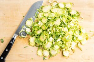 Picture of brussel sprouts being chopped with a knife.