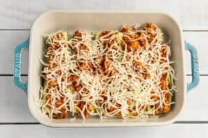 Picture of chicken zucchini boats with cheese in baking dish.