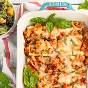 Picture of chicken zucchini boats in baking dish with side salad.