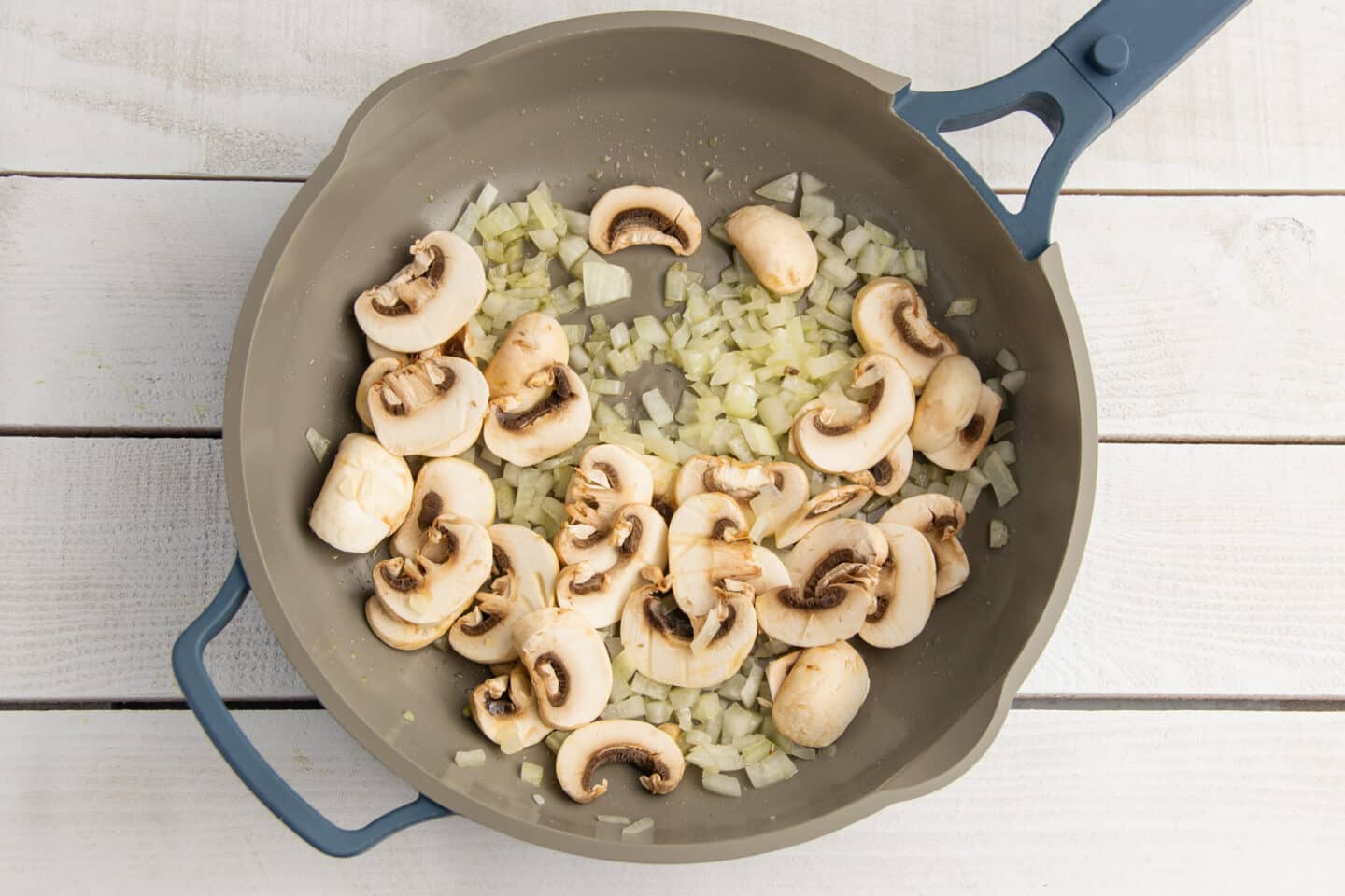 Picture of skillet with onion and mushrooms being cooked.