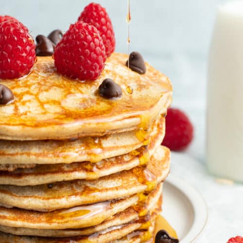 Picture of chocolate chip protein pancakes with raspberries and syrup.