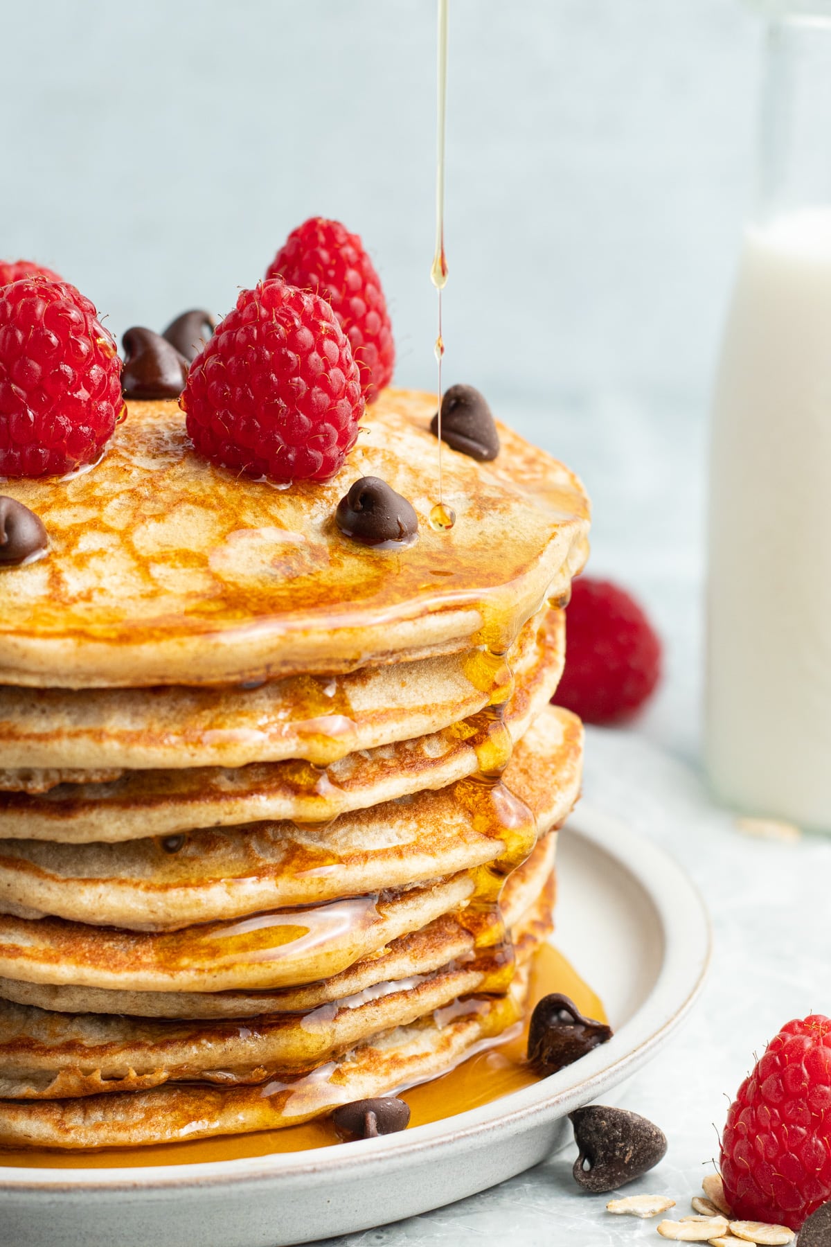 Picture of chocolate chip protein pancakes with raspberries and syrup. 