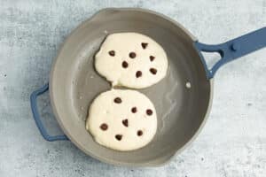 Picture of pan with pancakes batter with chocolate chips.