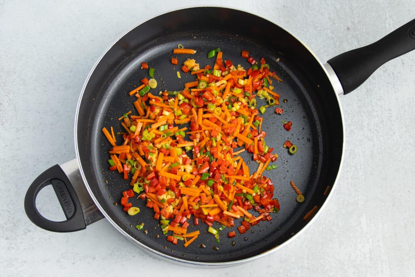 Picture of skillet with pepper, carrots, green onions, ginger and garlic cooking.