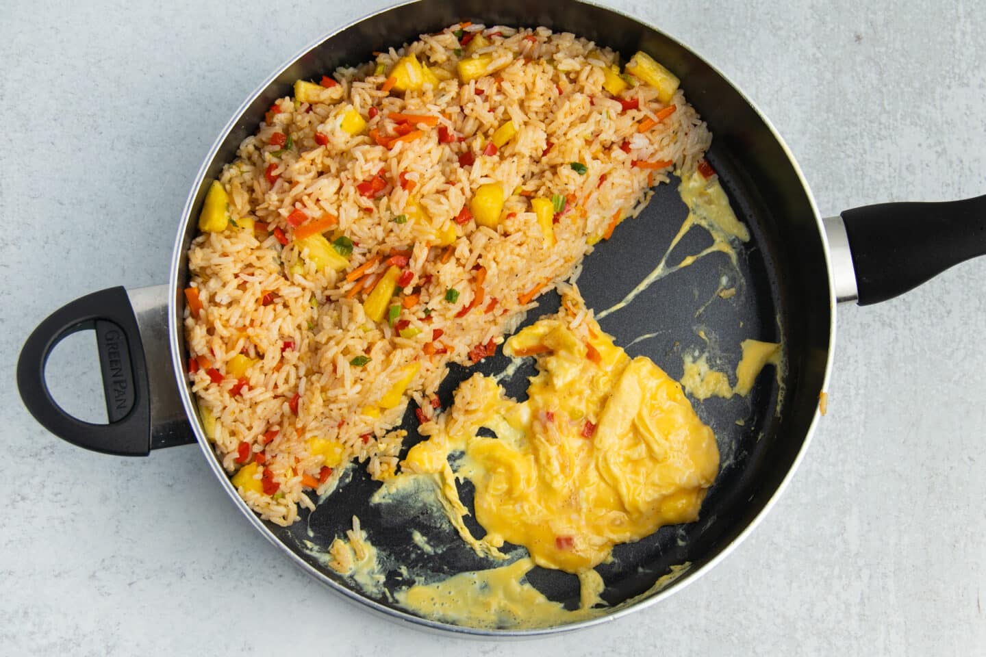 Picture of skillet with fried rice to one side and scrambled eggs on the other.