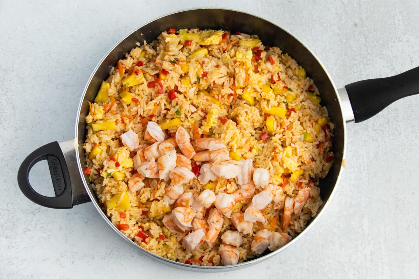 Picture of skillet with fried rice with shrimp added back in.