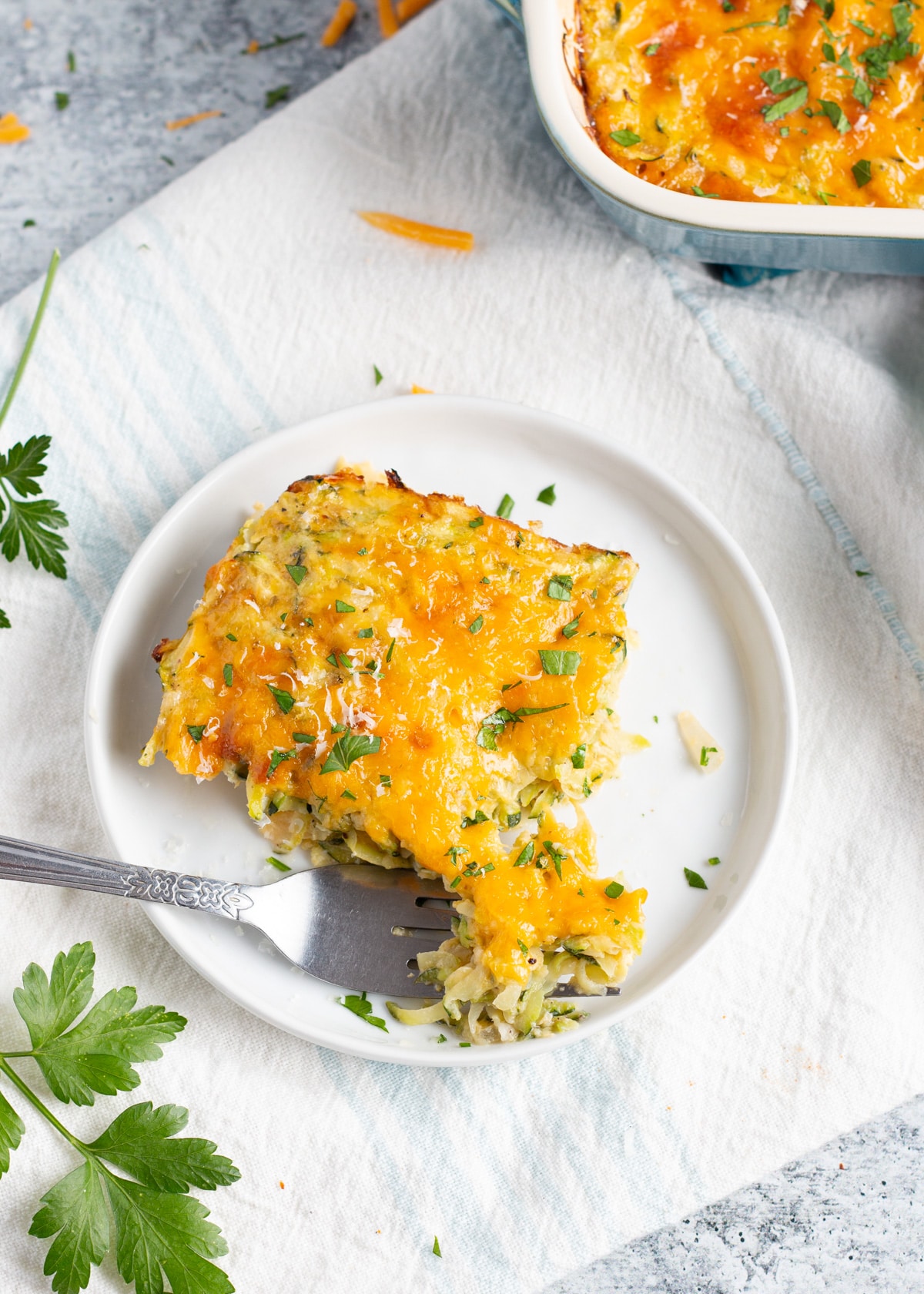 Image of a slice of the cheesy zucchini casserole in plate with a fork.