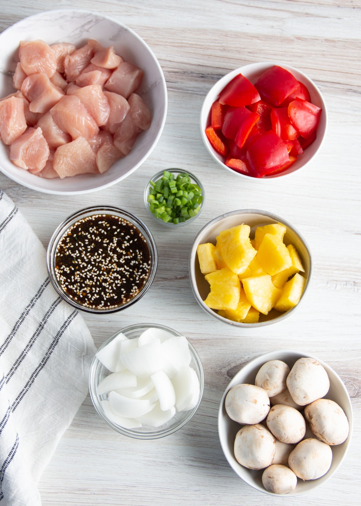 Picture of cut up ingredients in bowls. Chicken, pineapple, mushrooms, peppers, onion, teriyaki sauce, green onions.
