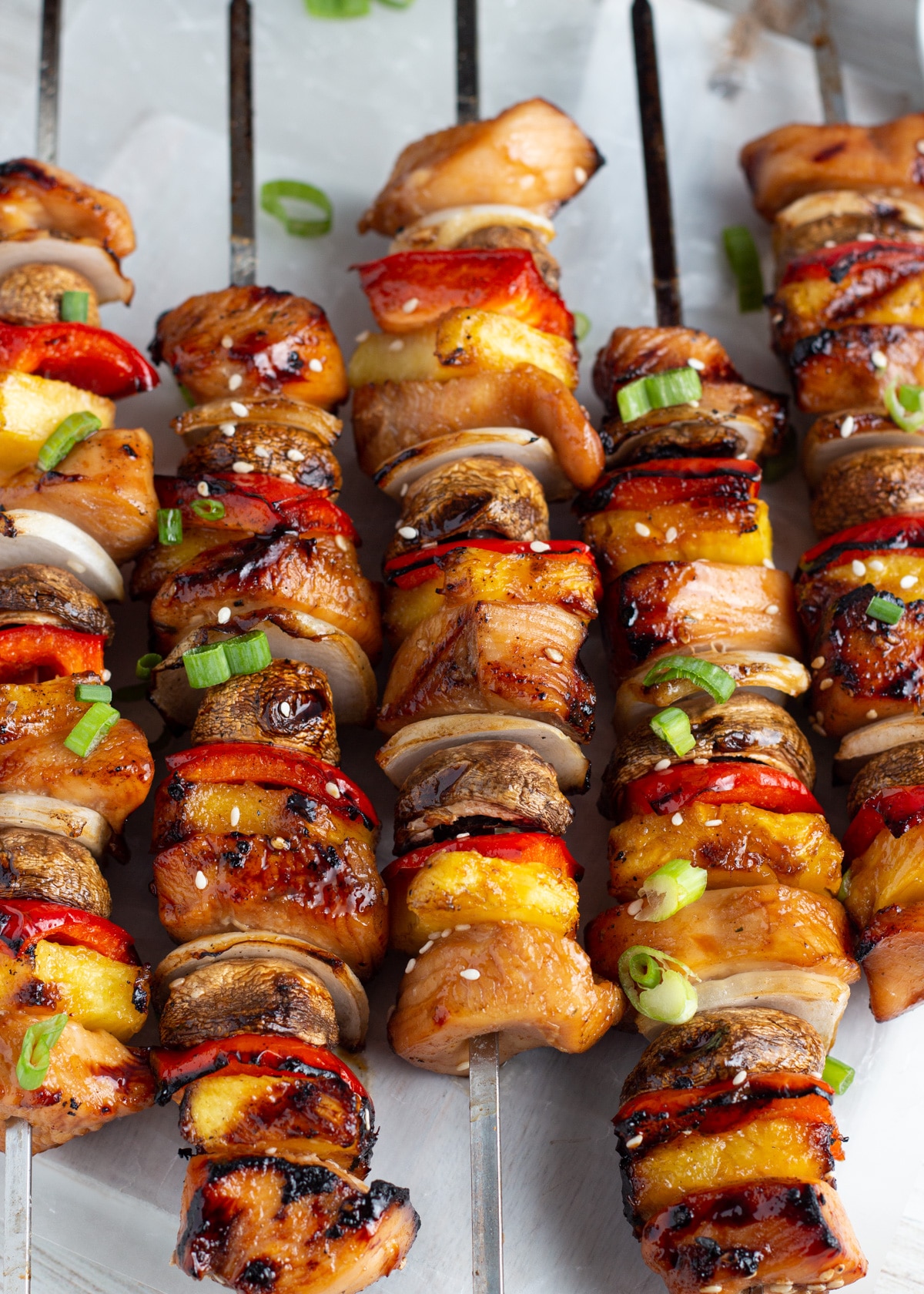 Close-up picture of cooked skewers with chicken, pineapple, mushrooms, onion and peppers.
