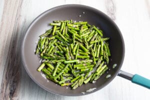 This is a picture of a skillet with asparagus cooking.