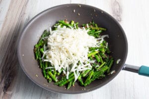 This is a picture of a skillet with asparagus and hasbrowns.