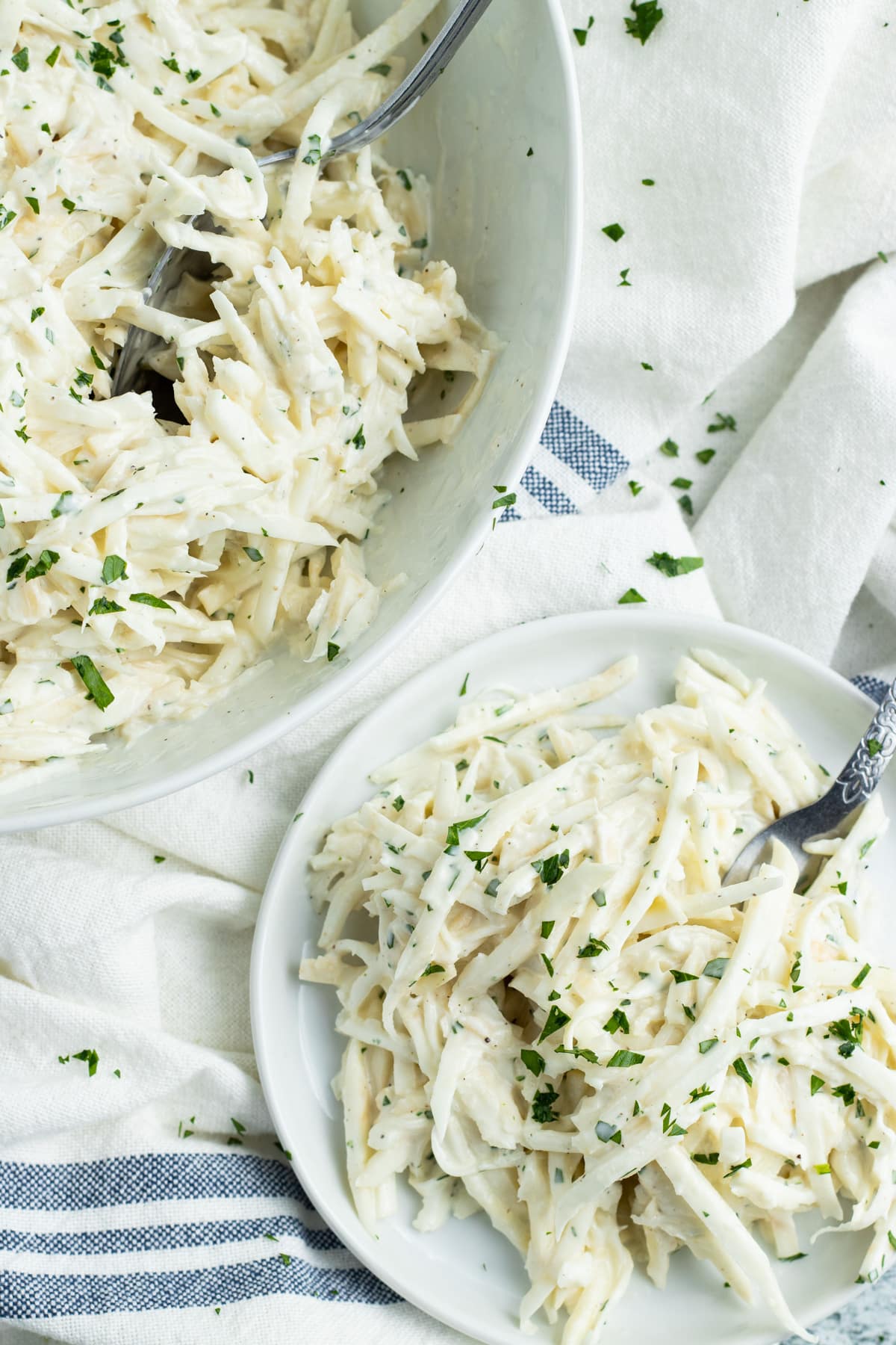 Photo of a bowl of celery root remoulade and a plate with some on it too. 