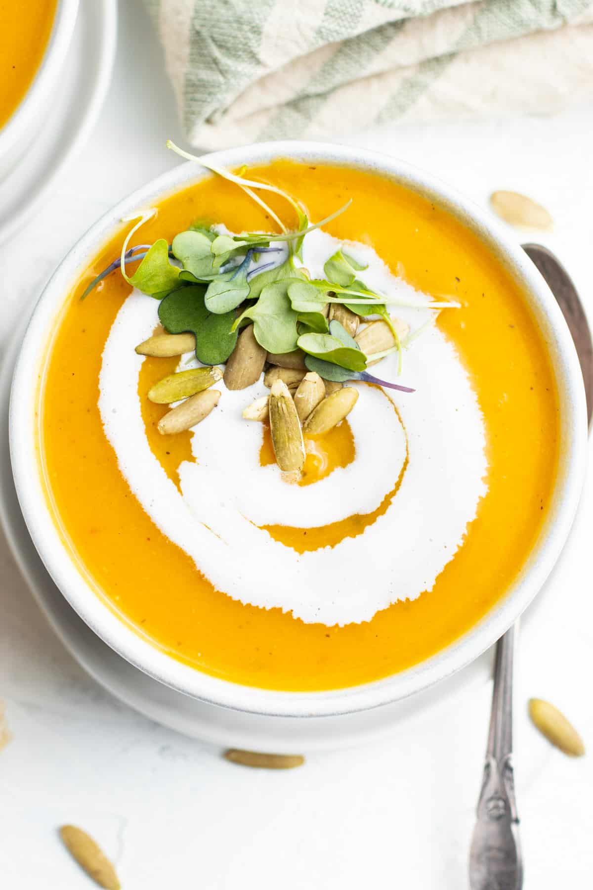 Picture of bowl of butternut squash leek soup with microgreens and pumpkin seeds. 