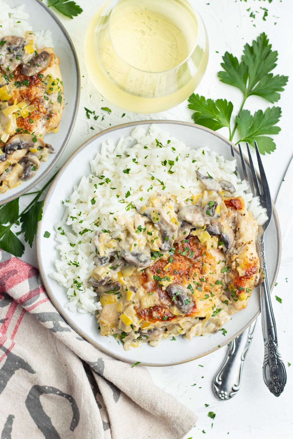 Photo of creamy dijon chicken with mushrooms and leeks with a glass of white wine.