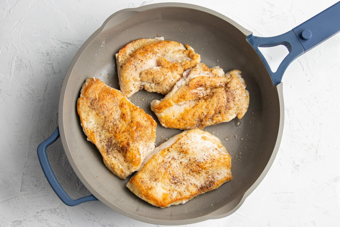 Photo of chicken being cooked in skillet. 