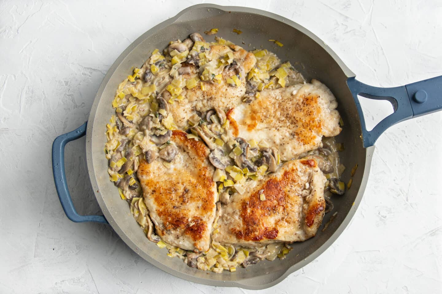 Photo of skillet after returning chicken to skillet with creamy mushroom and leek sauce. 