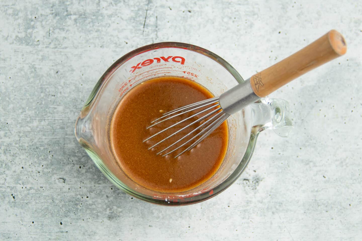 Image of stir fry sauce in bowl with whisk. 