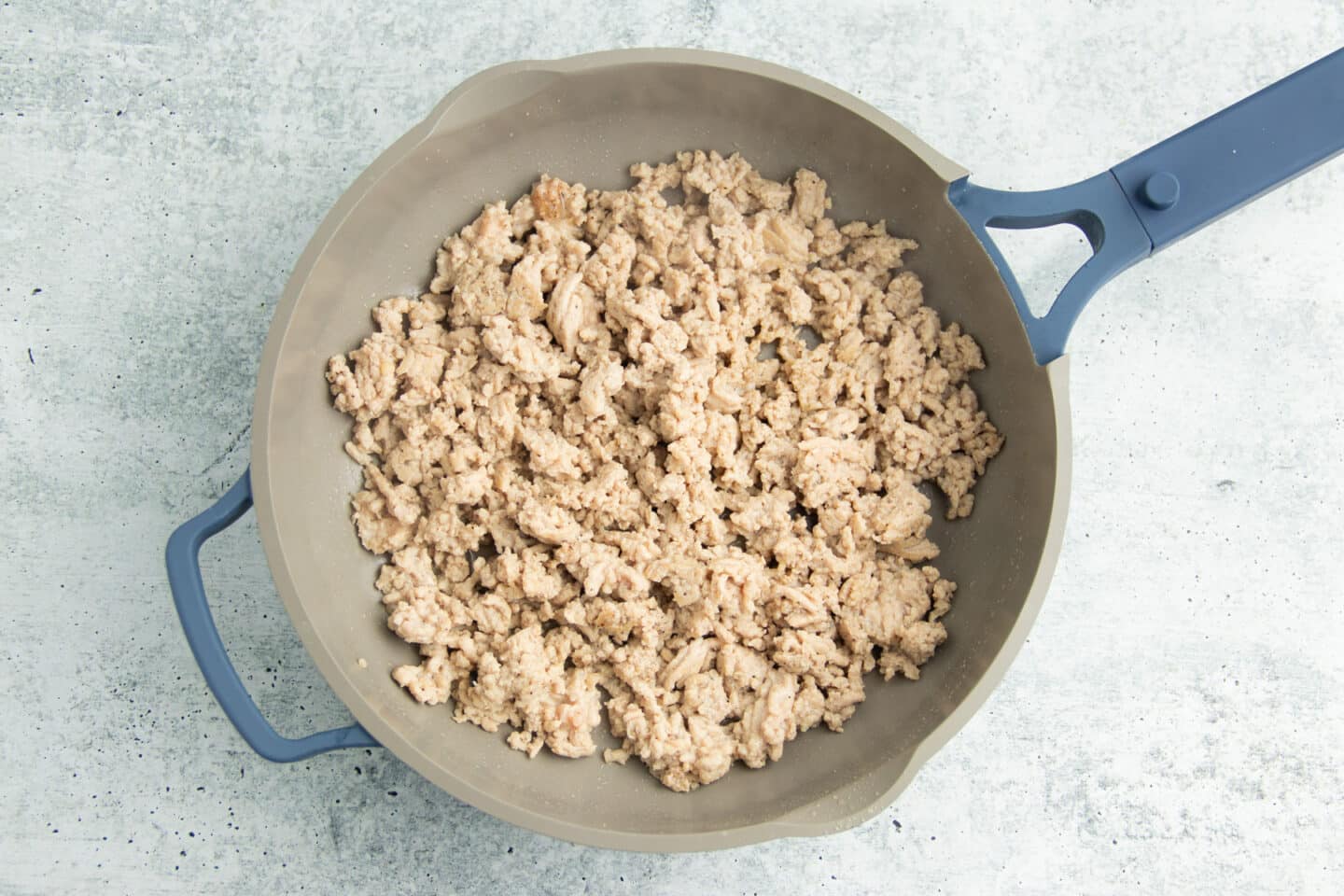 Picture of ground chicken being cooked into skillet.