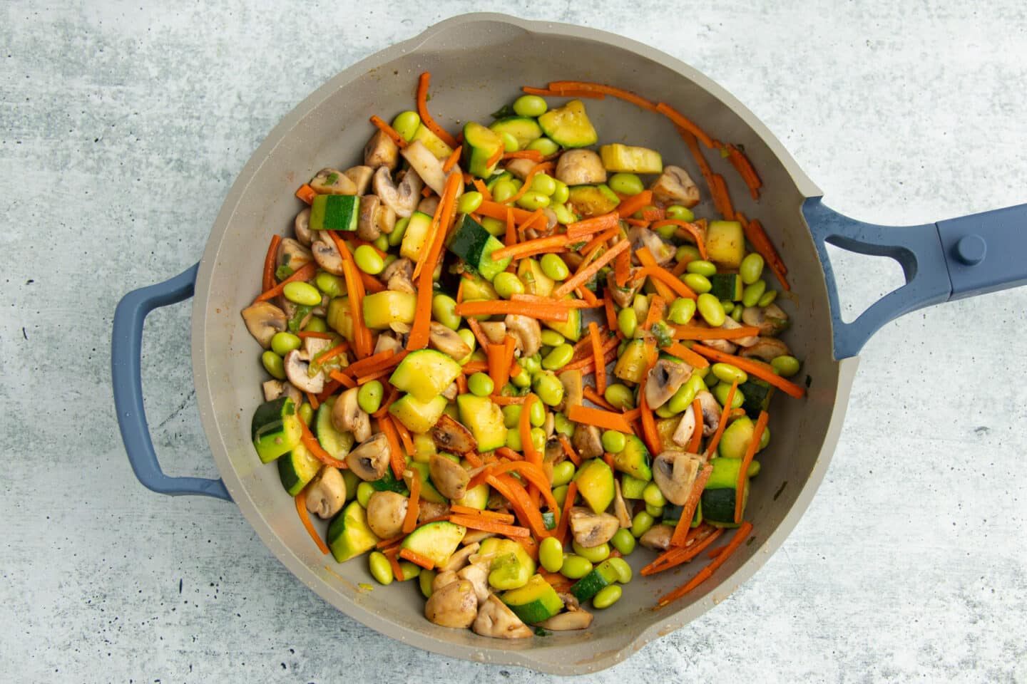 Picture of skillet with cooked vegetables and edamame added in.