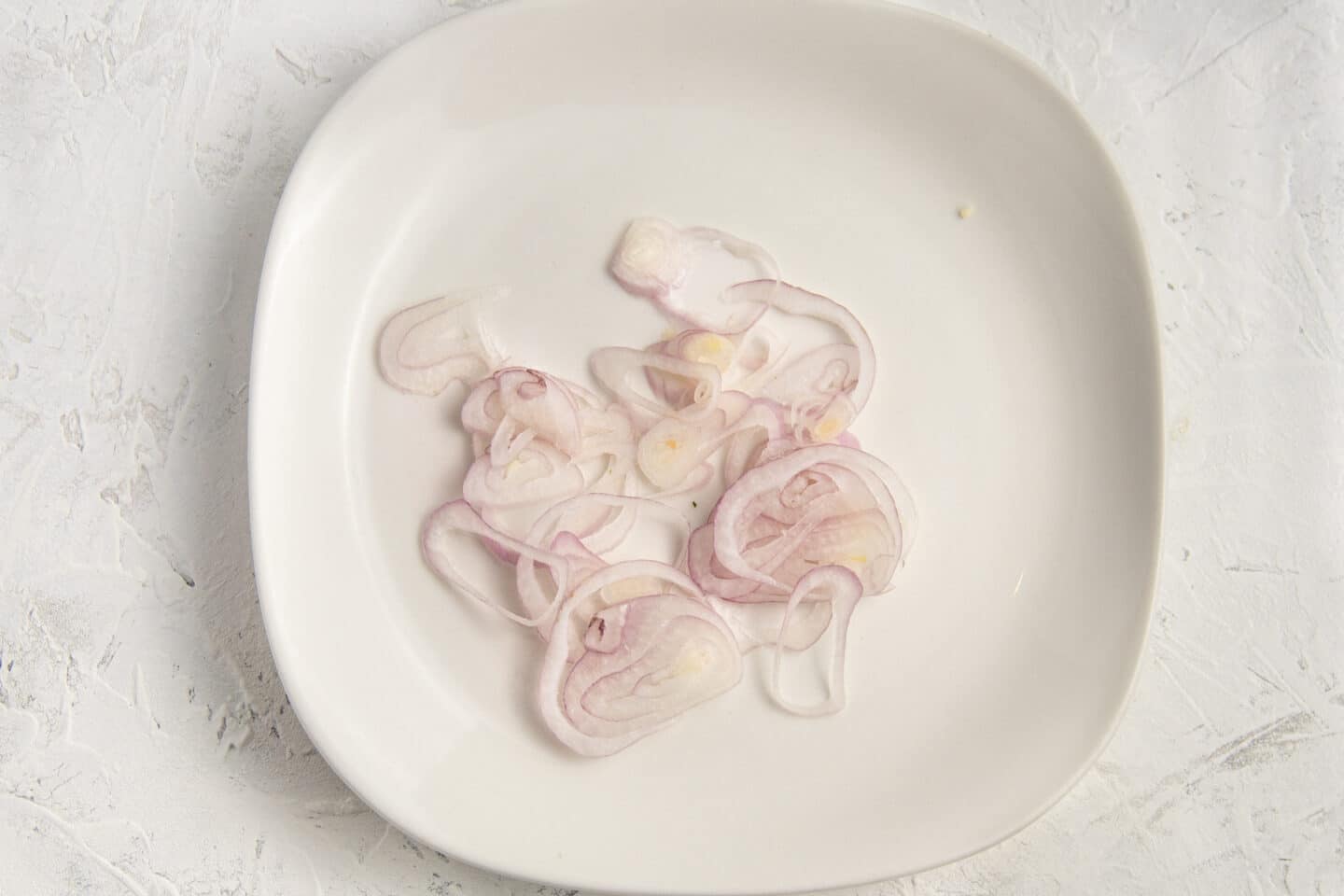 Picture of plate with thinly sliced shallots. 
