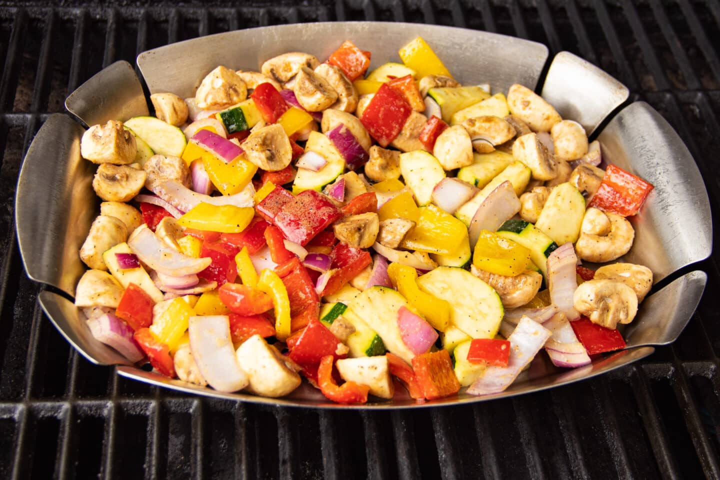 Picture of grill basket full of veggies on grill.