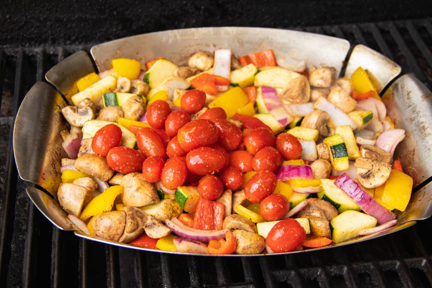 Picture of grilled basket with veggies with added cherry tomatoes. 