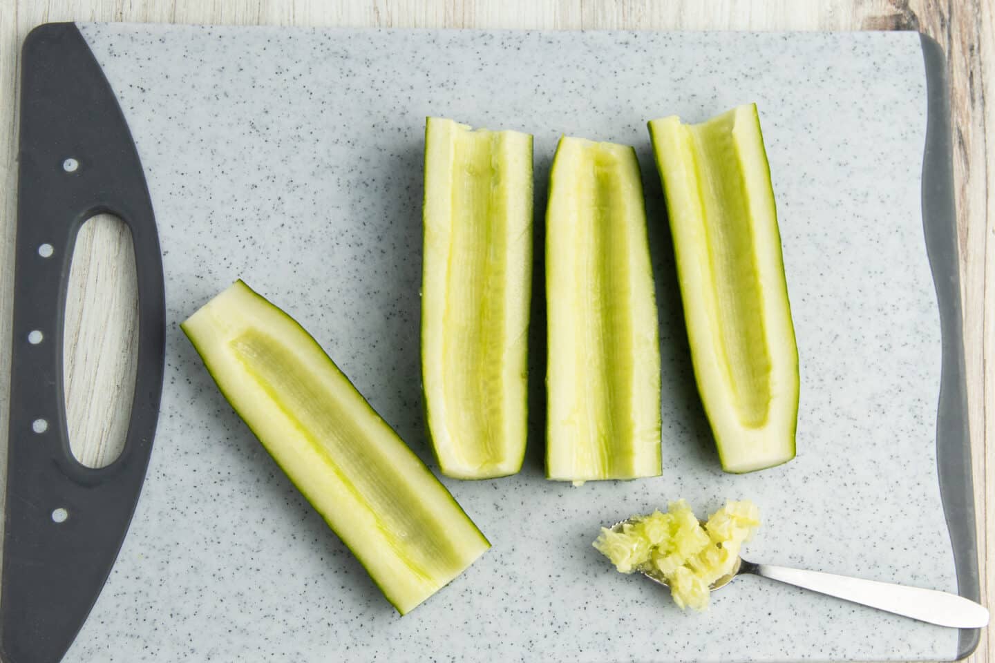 Picture of cucumbers cut in half with the seeds scooped out with a spoon.