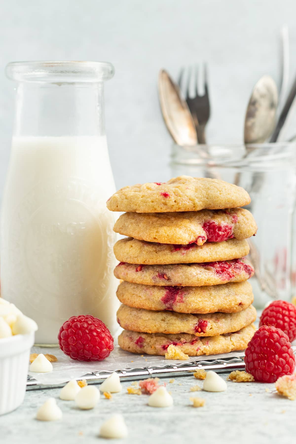 Picture of white chocolate raspberry cookies in a stack with a milk bottle. 