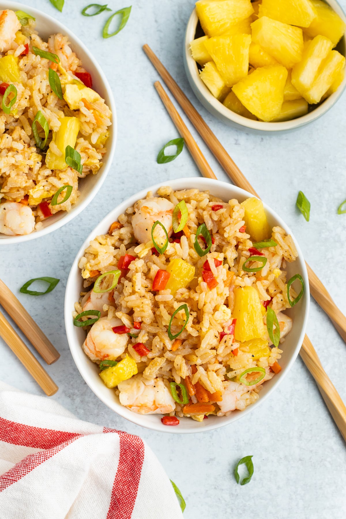 Picture of a two bowl filled with fried rice, a little bowl with pineapple and chopsticks. 