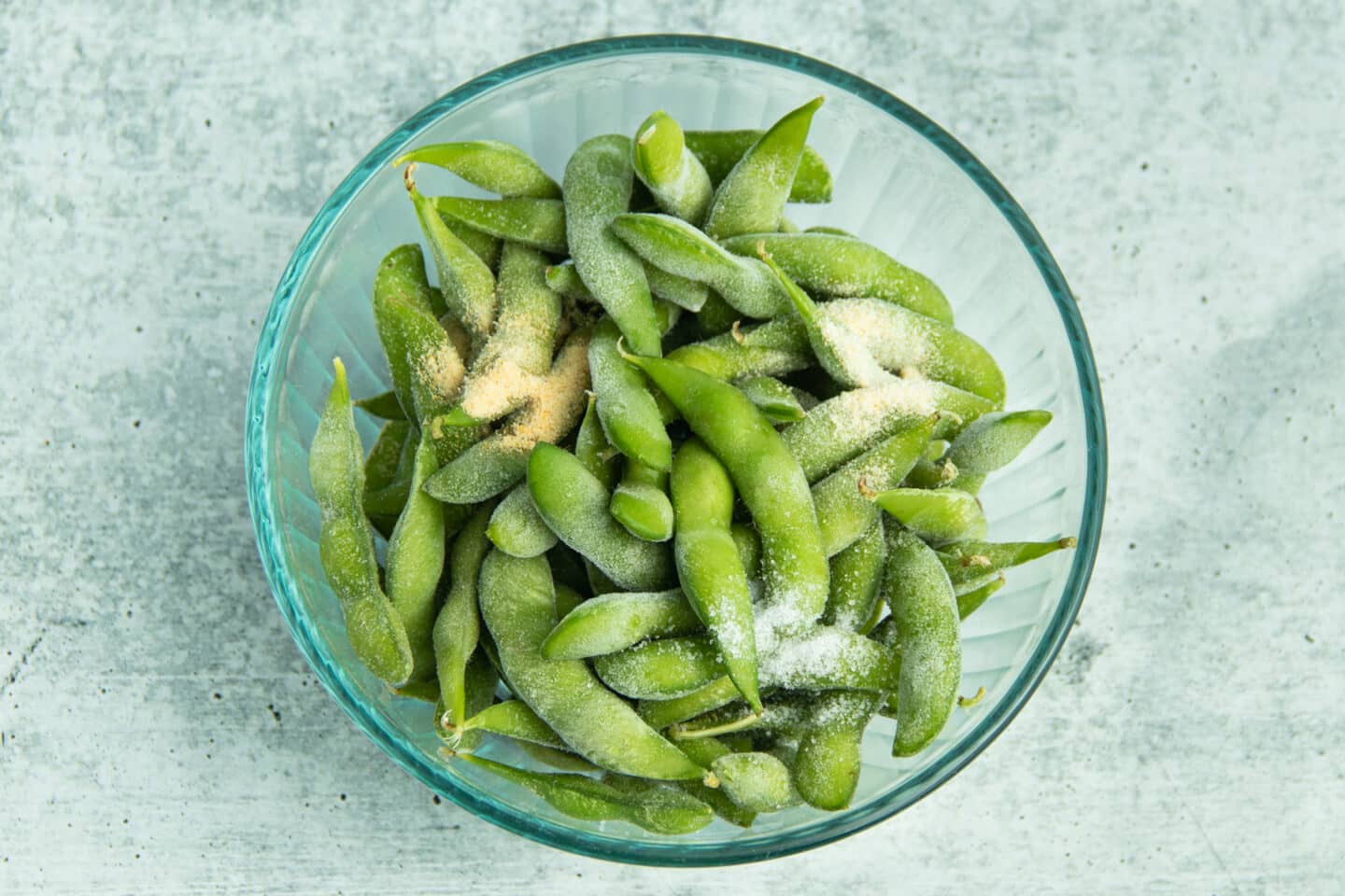 This is a picture of a bowl with frozen edamame with garlic powder, onion powder and salt.