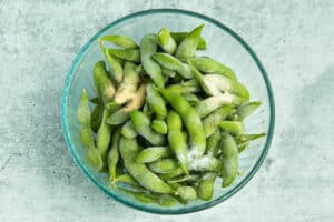 Picture of a large bowl filled with frozen edamame and seasoning.