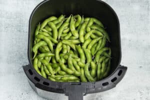 Picture of cooked edamame in air fryer basket.