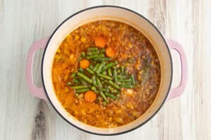 Picture of large pot with soup and green beans added.