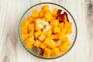 This is a picture of a bowl filled with raw butternut squash and spices on top.