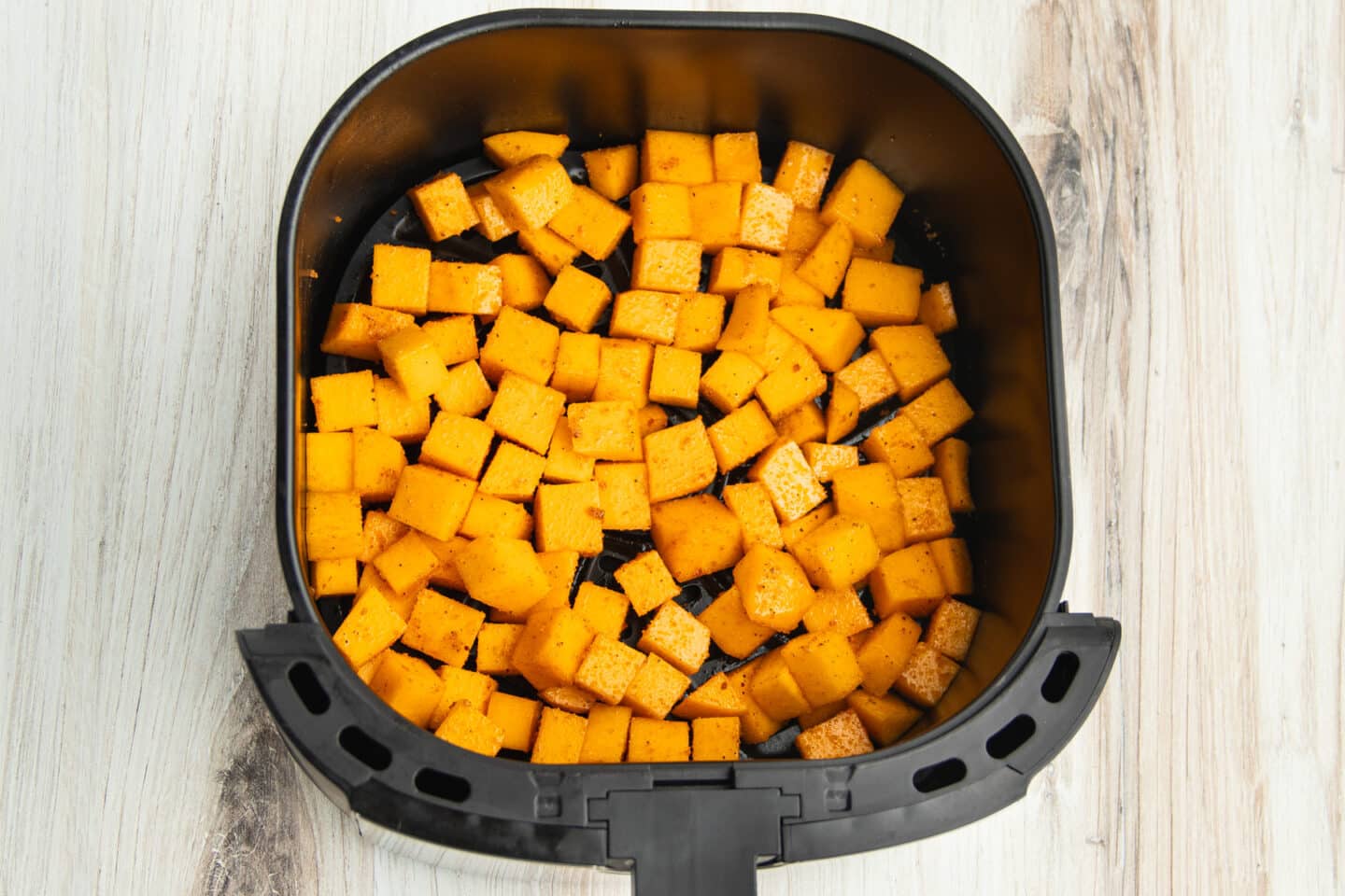 This is a picture raw butternut squash in the air fryer before cooking.