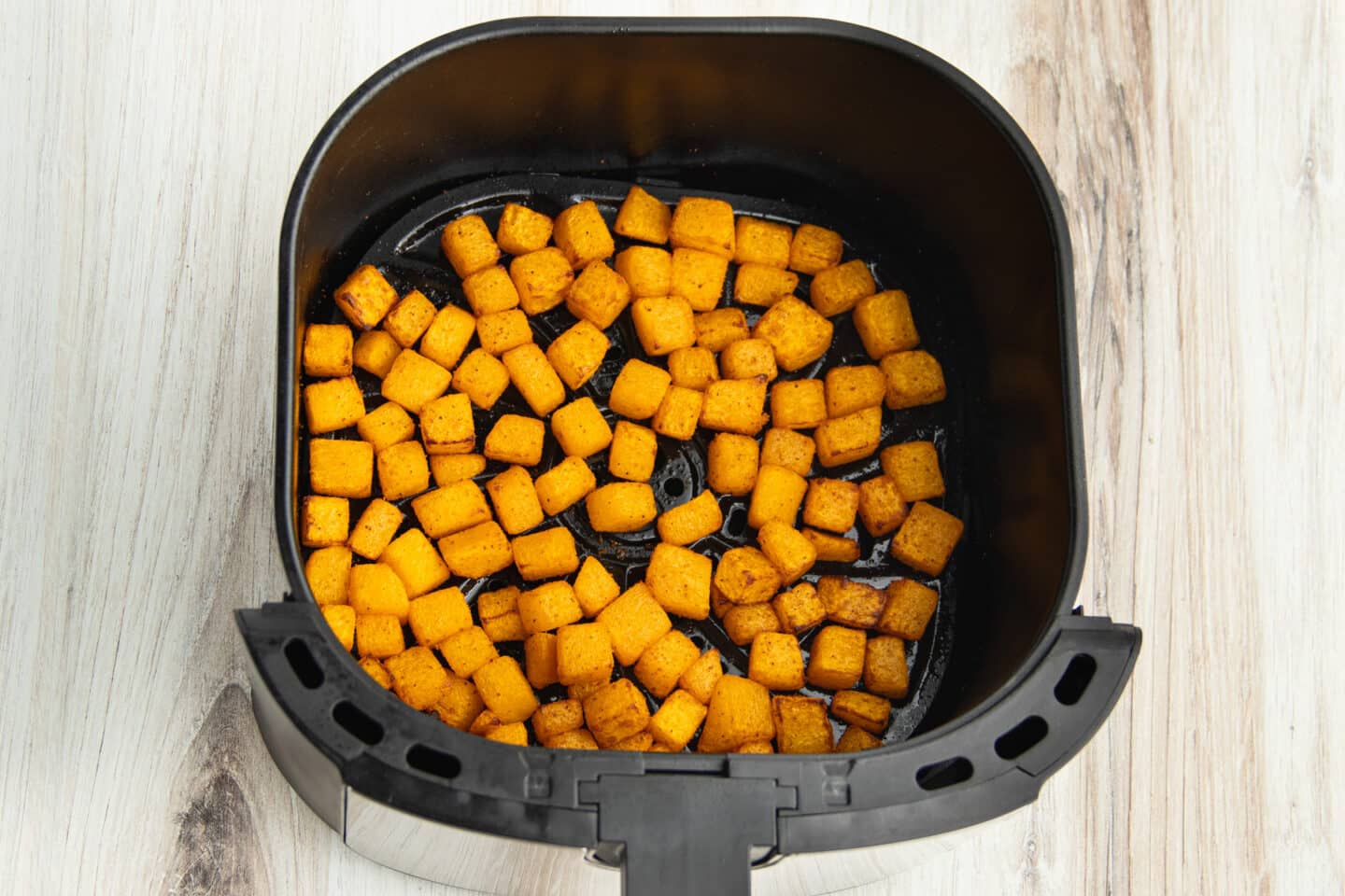 This is a picture of butternut squash in the air fryer after cooking.