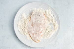 This is a picture of a chicken cutlet being dipped in flour.