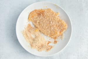 This is a picture of a chicken cutlet being dipped in panko.