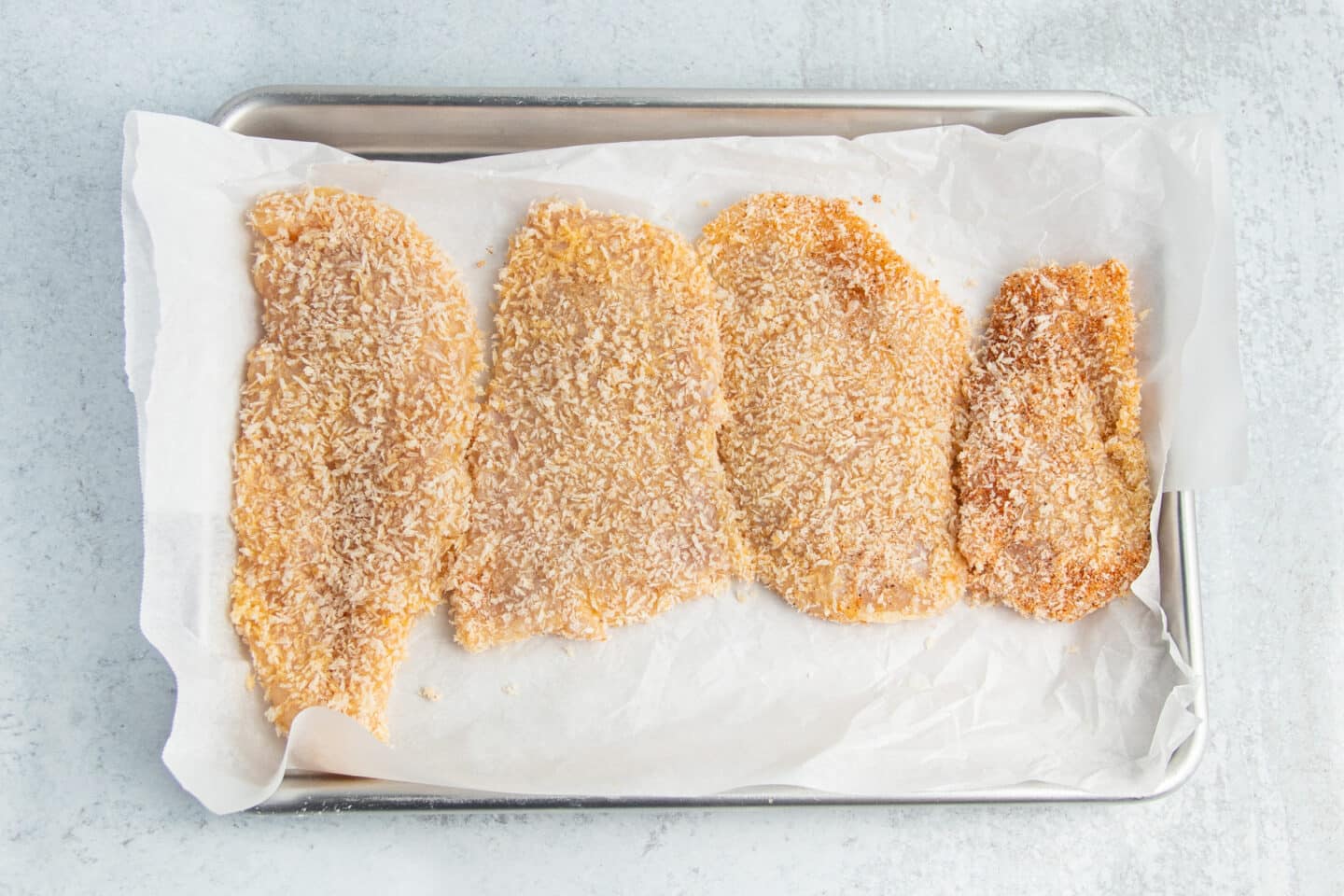 This is a picture of a chicken cutlets on a baking sheet ready to be air fried.