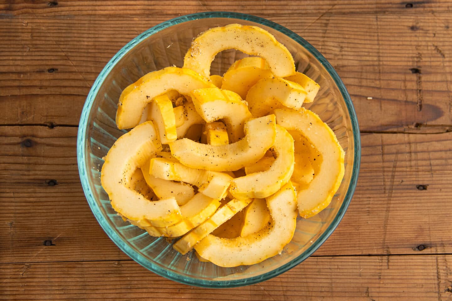 Picture of cut delicata squash in a bowl with spices.