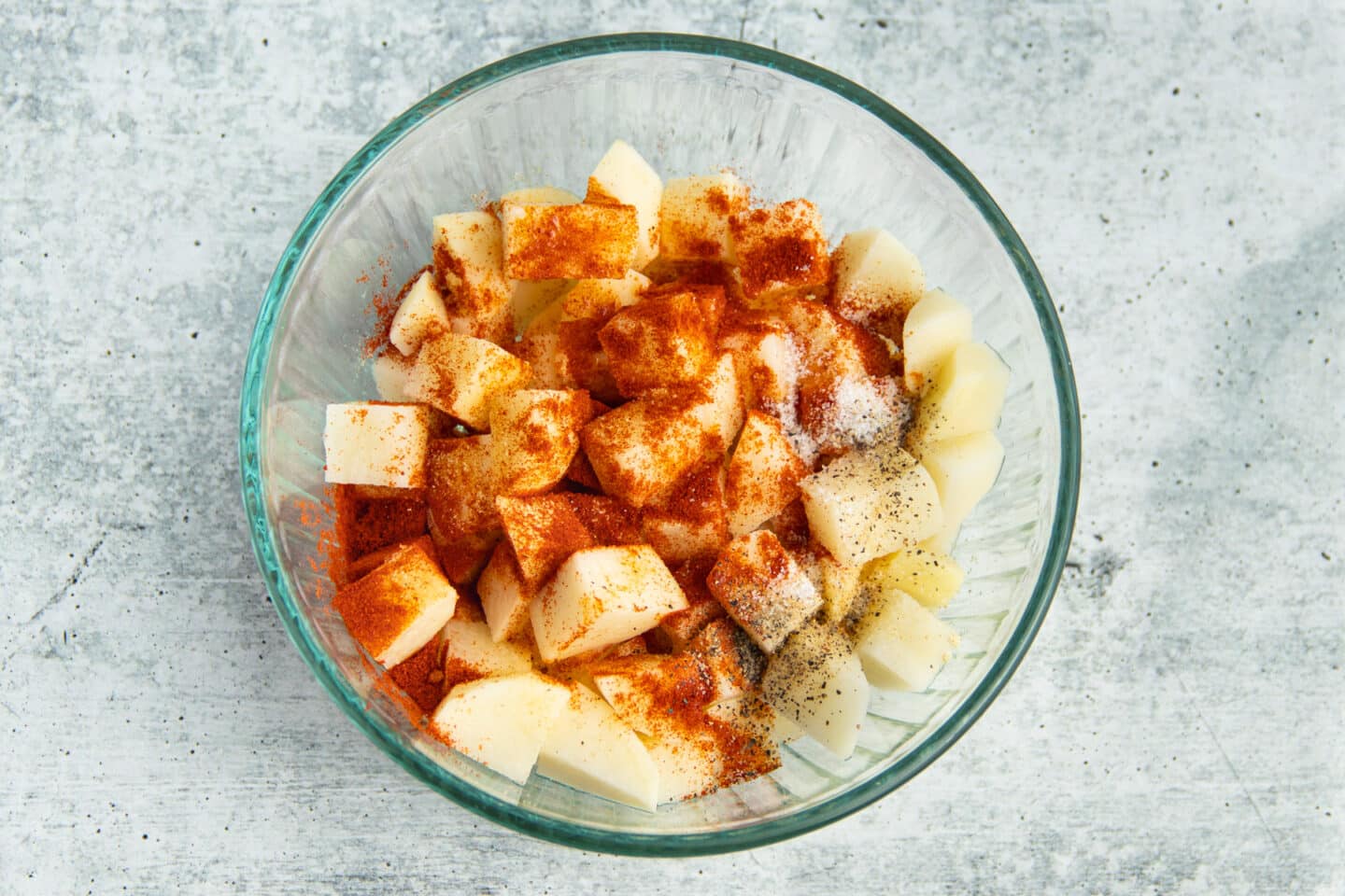 Picture of a bowl with diced potatoes and spices on top.