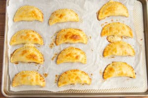 This is a picture of a baking sheet filled with cooked empanadas after baking them.