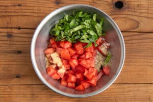 This is a picture of bowl with tomatoes, basil, and spices.