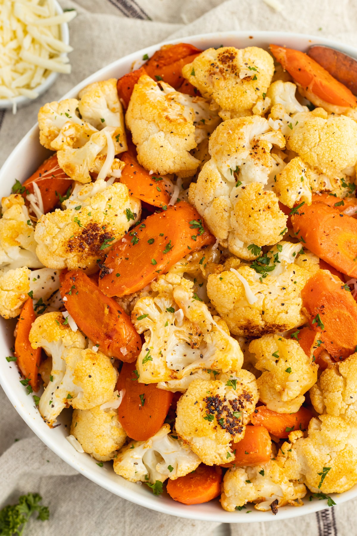 This is a picture of a bowl filled with cheesy roasted carrots and cauliflower.