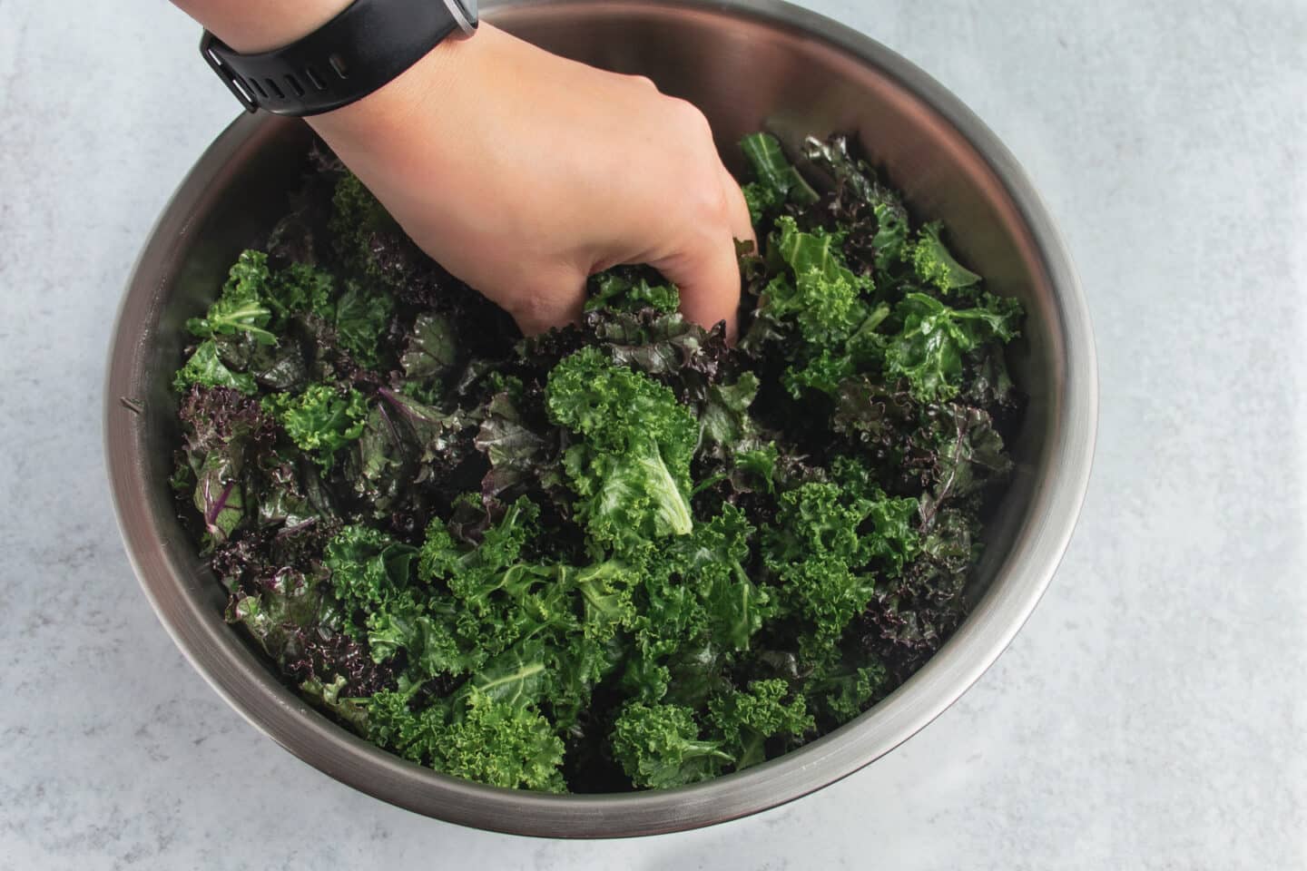 Picture of kale in a large bowl being massaged.