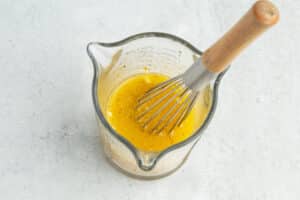 This is a picture of a cup with the orange vinaigrette and a whisk.