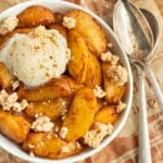 This is a picture of a bowl with cooked apples with ice cream and granola.