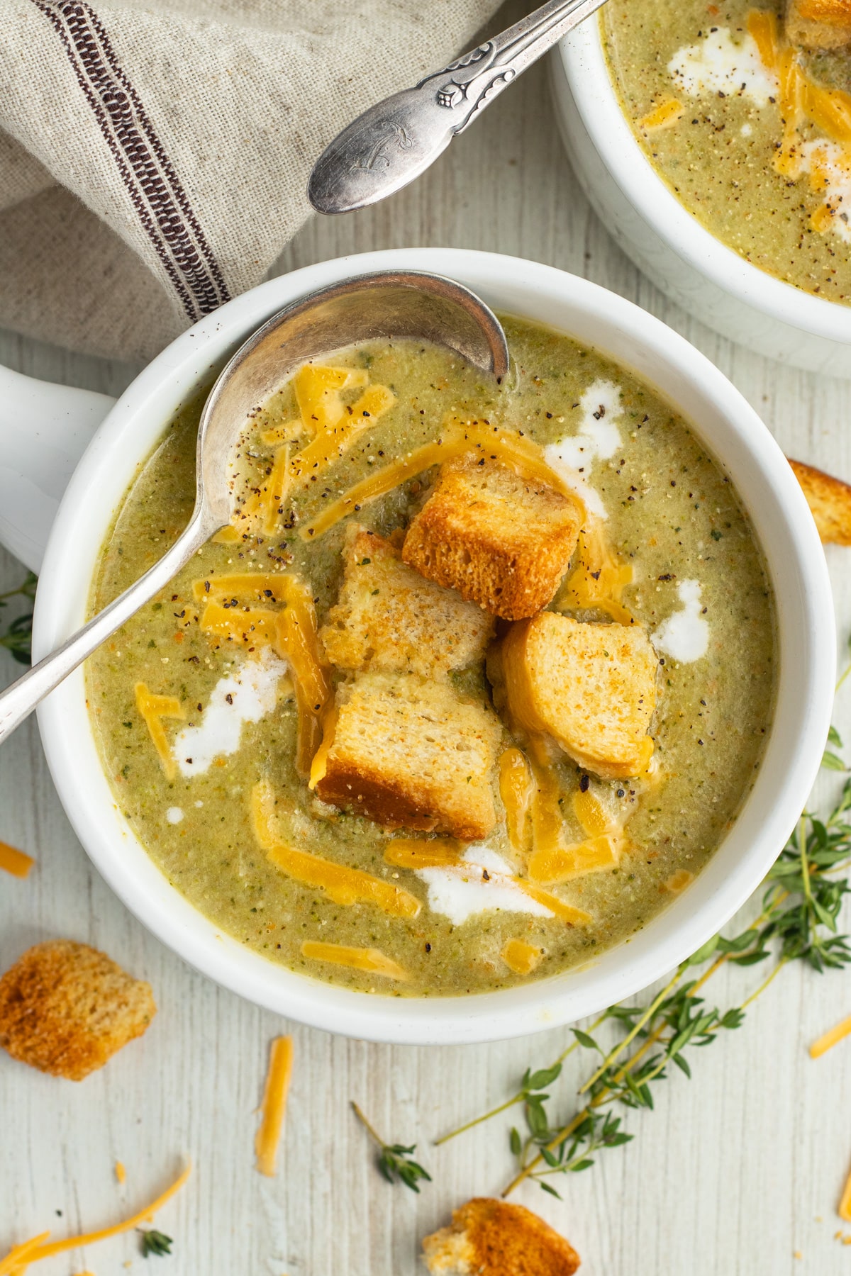 This is a picture of a bowl with broccoli zucchini soup topped with croutons.